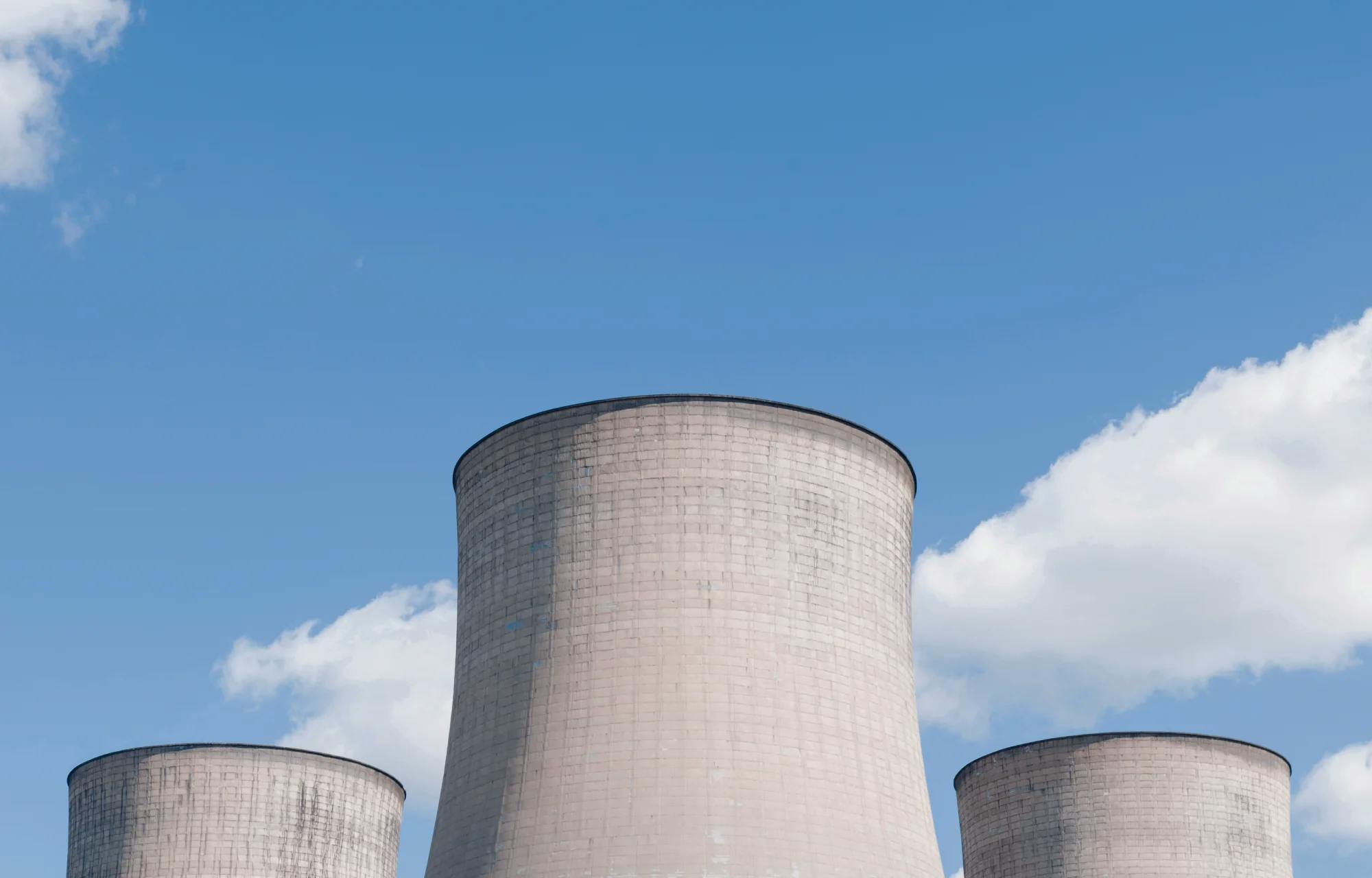 Cooling towers over a blue sky with scattered clouds